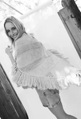 Poncho de tejido de algodón color beige claro, con diseño de punto calado y flecos en el borde inferior.