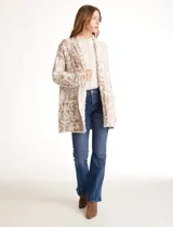 Cardigan abierto de tejido soft, marca Ruby Rd., con patrón de arabescos en relieve en tonos beige y blanco. Tiene cuello solapa fluido, mangas largas de corte recto y bolsillos aplicados en la parte delantera.