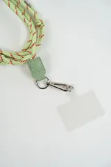 Correa para celular de cuerda trenzada en tonos naranja y fucsia, con detalle de cuero sintético naranja y gancho metálico tipo mosquetón que incluye una placa transparente para sujeción.