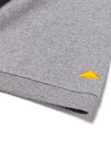 Remera polo gris melange de manga corta Caterpillar, con franjas horizontales en tonos verde oscuro y menta en el pecho, cuello camisero con botones y parche de silicona con logo.