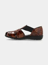 Sandalia anatómica tipo cangrejera de cuero con estampado animal print tipo carey y acabado charolado. Cuenta con tiras elásticas negras laterales, puntera cerrada con aberturas y suela flexible de goma.