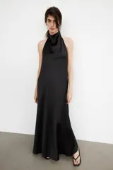 Vestido largo de satén con cuello halter y escote fluido. Presenta un diseño de espalda descubierta con cierre de cremallera oculta y lazada ajustable en el cuello.