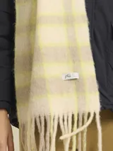 Bufanda de tejido suave con diseño a cuadros en tonos beige y amarillo neón. Presenta flecos en los extremos y una etiqueta de la marca Rusty.