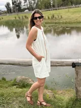 Vestido corto de jean crudo, de silueta holgada y sin mangas, con una tira vertical central de cuero color camel y bolsillos laterales.