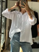 Camisa básica de corte oversize confeccionada en crepé de seda, con cuello clásico, cierre frontal de botones y mangas largas con puños.