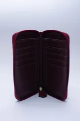 Billetera chica de cuero negro con textura tipo cocodrilo, cierre exterior, bolsillo para monedas con cierre en la parte trasera, múltiples ranuras para tarjetas y billetes, y forro rojo.