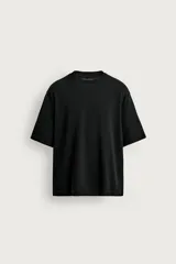 Camiseta boxy fit de punto color negro, confeccionada en hilatura de algodón, con cuello redondo, manga corta y efecto lavado.