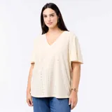 Camiseta de manga corta y cuello en V, confeccionada en tejido de punto calado con sutiles perforaciones geométricas, de corte holgado y diseño versátil.