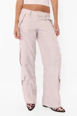 Pantalón cargo negro de corte recto y tiro bajo, con recortes y múltiples bolsillos laterales y traseros con tapa y botón a presión. Cierre frontal con cremallera de nylon y botón personalizado.