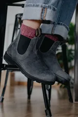 Botas tipo chelsea Blundstone modelo #1910, confeccionadas en gamuza gris repelente al agua. Presentan elásticos laterales negros, tiradores en la parte superior y suela de TPU antideslizante con entresuela acolchada para mayor confort.