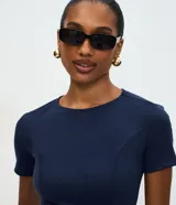 Blusa de punto roma color azul marino, con diseño estructurado, manga corta, recortes que definen la silueta, detalles de lazos decorativos en el frente y ruedo con volado peplum.