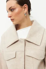 Tapado corto gris de paño, con cuello solapa grande, bolsillos de parche con solapa y mangas largas con puños anchos con presilla y aro metálico.