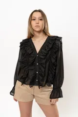 Camisa negra de gasa con escote en V, doble volado frontal, mangas largas abullonadas con puños elásticos y cierre frontal con botones.