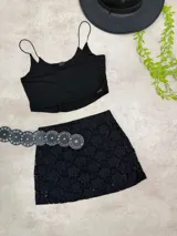 Minifalda de encaje negro con diseño floral y forro interno. Presenta un calce ajustado al cuerpo y un detalle de transparencias en el ruedo.