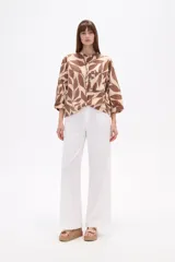 Camisa de corte holgado con estampado animal print tipo cebra en tonos negro y beige. Presenta cuello mao, cierre frontal con botones y un bolsillo aplicado en el pecho.