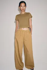 Pantalón de tiro medio con pierna ancha y cintura elástica, confeccionado en mezcla de viscosa con diseño de rayas verticales en tonos mostaza y marrón.
