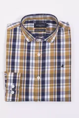 Camisa de manga larga Brooksfield con diseño a cuadros en tonos mostaza, azul marino y blanco. Presenta cuello clásico, cierre frontal con botones y logo bordado en el pecho.