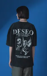 Remera de algodón premium con efecto nevado, corte oversize y cuello redondo. Presenta una estampa gráfica en color blanco en la espalda que incluye la palabra 'DESEO', una ilustración de una rosa y una figura alada, junto con frases poéticas.