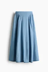 Pollera acampanada de denim color celeste, modelo largo de corte evasé con frunces en la cadera para mayor volumen.