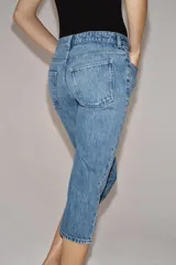 Jeans capri de tiro medio con diseño de cinco bolsillos, cintura con trabillas y cierre frontal con cremallera y botón. Presenta un acabado con efecto lavado.