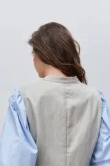 Chaleco de calce entallado color beige, de estilo cruzado con doble botonadura y escote redondo.