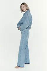 Jean de tiro alto con corte wide leg y piernas amplias. Confeccionado en denim de algodón con leve stretch, presenta diseño de cinco bolsillos, cierre con botón y bajo con detalle de ruedo desgastado.