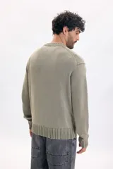 Buzo tejido lavado de color verde militar, con cuello redondo, mangas largas y puños y cintura de rib elástico.
