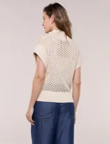 Buzo de punto color marfil, confeccionado en algodón calado con cuello alto acanalado y medio cierre metálico dorado. Presenta mangas cortas estilo japonesa con puños anchos y un zócalo acanalado en el ruedo.