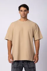 Remera de corte oversized en color marrón, confeccionada en tejido de algodón con textura de micropanal. Presenta cuello redondo con detalle de costura en forma de X y mangas cortas de estilo caído.