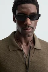 Polo negro de manga corta con cuello solapa y abertura frontal. Presenta un tejido jacquard con textura geométrica sutil.