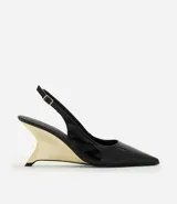 Zapato slingback de punta fina en material sintético efecto charol negro, con tacón anabela de diseño arquitectónico en acabado dorado cromado y tira trasera ajustable con hebilla.