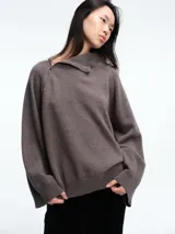 Sweater de lana superfina color gris, con corte holgado, mangas largas y cuello alto con medio cierre lateral.