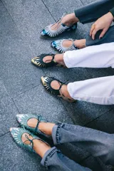 Zapato tipo blucher de cuero con acabado metalizado en color azul petróleo y estampado de estrellas blancas. Presenta un diseño con flecos decorativos en la parte frontal, cierre con cordones y suela plana de cuero.