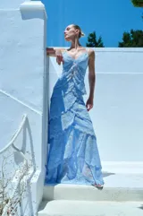 Vestido largo celeste de encaje con diseño de volados escalonados en la falda, tirantes finos y escote pronunciado con detalles de aberturas frontales.