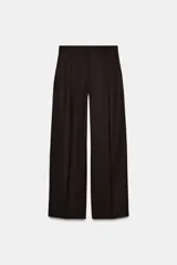 Pantalón de tiro medio y pernera recta color marrón oscuro, con pinzas delanteras, bolsillos frontales y cierre con cremallera y botón.