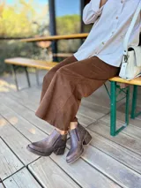 Botas cortas de cuero con efecto desgastado en color chocolate, con taco cuadrado y plataforma. Presentan cierre lateral y punta redondeada.