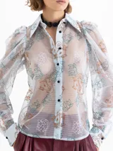 Camisa transparente de mesh rayado con bordados de dragones en verde y naranja. Tiene cuello clásico, botones negros forrados, puños de popelina y mangas abullonadas.