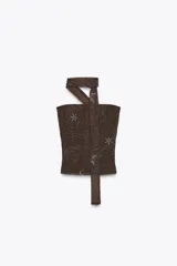 Top tipo corset o bandeau color marrón oscuro, con bordado de cuentas y lentejuelas blancas que forman patrones florales y asteriscos. Incluye un largo lazo/foulard a juego que funciona como tirante halter y se extiende hacia abajo.