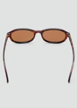 Lentes de sol Femme con montura ovalada de pasta con estampado carey y cristales marrones.