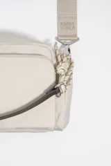Bolso tipo morral Bimba y Lola, de color tostado, confeccionado en nylon suave con detalles en cuero y tirantes de cordón. Cuenta con múltiples compartimentos con cierre y el logo metálico de la marca en el frente.