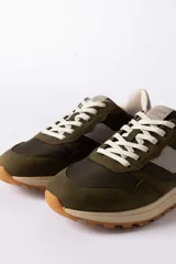 Championes urbanos de diseño técnico, combinando paneles de gamuza y tela en tono verde oliva con detalles en beige y negro. Presentan una suela de plataforma en color crema con base dentada en tono caramelo.