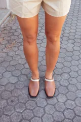 Mules de cuero color tostado con detalle de tira beige en el empeine y suela negra.