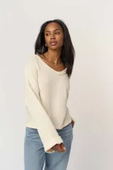 Remera de manga larga de tejido de punto suave color beige, con cuello en V y calce relajado.