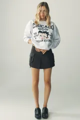Falda pantalón negra de tiro medio, confeccionada en algodón, con pliegue frontal y maxi bolsillos cargo con solapa y cremallera en ambos lados.