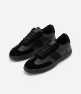 Championes urbanos para hombre en color negro, con diseño monocromático de perfil bajo. Combinan inserciones de material sintético y textura tipo gamuza en la puntera y laterales, con cierre de cordones al tono.