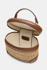 Bolso tipo vanity combinado en rafia y efecto cuero marrón, con cuerpo de tejido trenzado, detalles de pespuntes, asa de mano superior y cierre de cremallera.