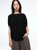 Top de tejido de punto negro con sutiles micro lentejuelas brillantes. Presenta una silueta amplia y holgada, cuello redondo y mangas cortas caídas.