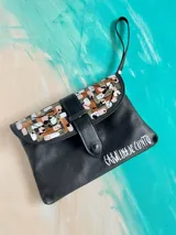 Sobre de mano Carolina de Cunto de cuero negro con diseño artístico pintado a mano en la solapa, mango corto de mano y cierre con broche magnético.