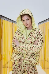 Campera puffer amarilla con estampado abstracto en color borgoña, con capucha y cierre frontal con botones a presión.