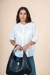 Blusa de algodón color blanco con bordado sutil en relieve, cuello redondo, cierre frontal con botones y mangas tres cuartos con terminación elástica.